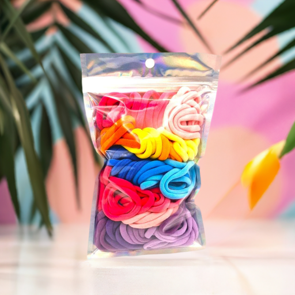 Girl's Hair Ties: ENAX Multi-Coloured Hair Bands, One silver pack of (ENAX) colorful medium-sized Hair Ties. 80 hair ties inside each pack. Pink coloured, flowery background. Front Side.