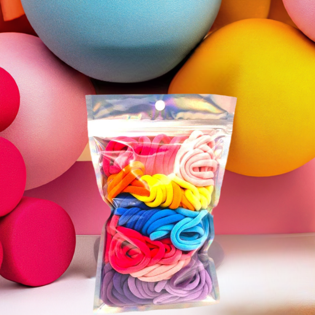 Girl's Hair Ties: ENAX Multi-Coloured Hair Bands, One silver pack of (ENAX) colorful medium-sized Hair Ties. 80 hair ties inside each pack. Bold coloured geometric background. Front Side.