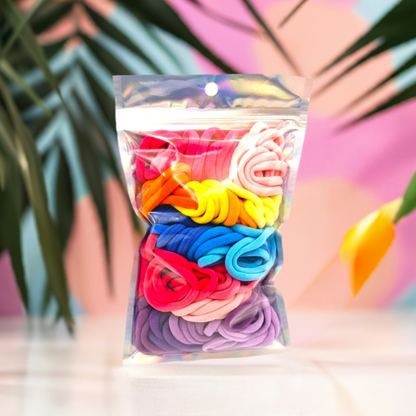 Girl's Hair Ties: ENAX Multi-Coloured Hair Bands, One silver pack of (ENAX) colorful medium-sized Hair Ties. 80 hair ties inside each pack. Pink coloured, flowery background. Front Side.