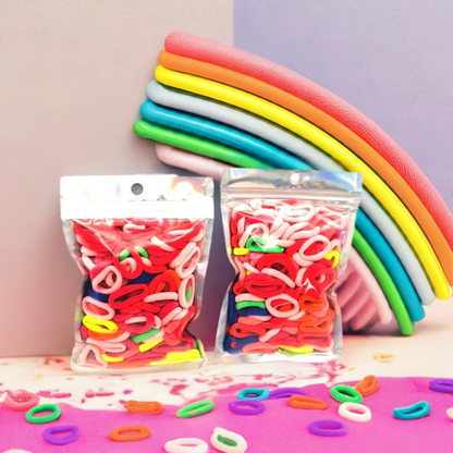 Baby & Toddler's Hair Ties Pack of 2: ENAX Hair Bands, Two silver packet of (ENAX) colorful small sized Hair Ties. Mostly light and dark Pink coloured Hair Ties. 120 hair ties inside each pack, two packets in picture.  Colourful background with rainbow foams displayed. Transparent Front side.